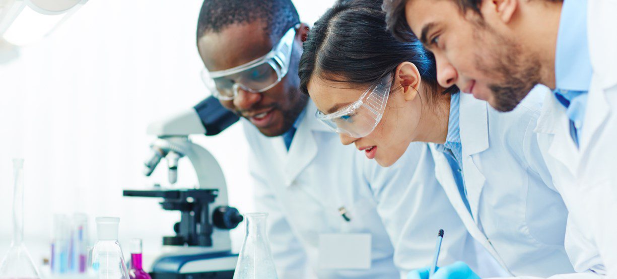 Young scientists analyzing blue liquid substance in tube